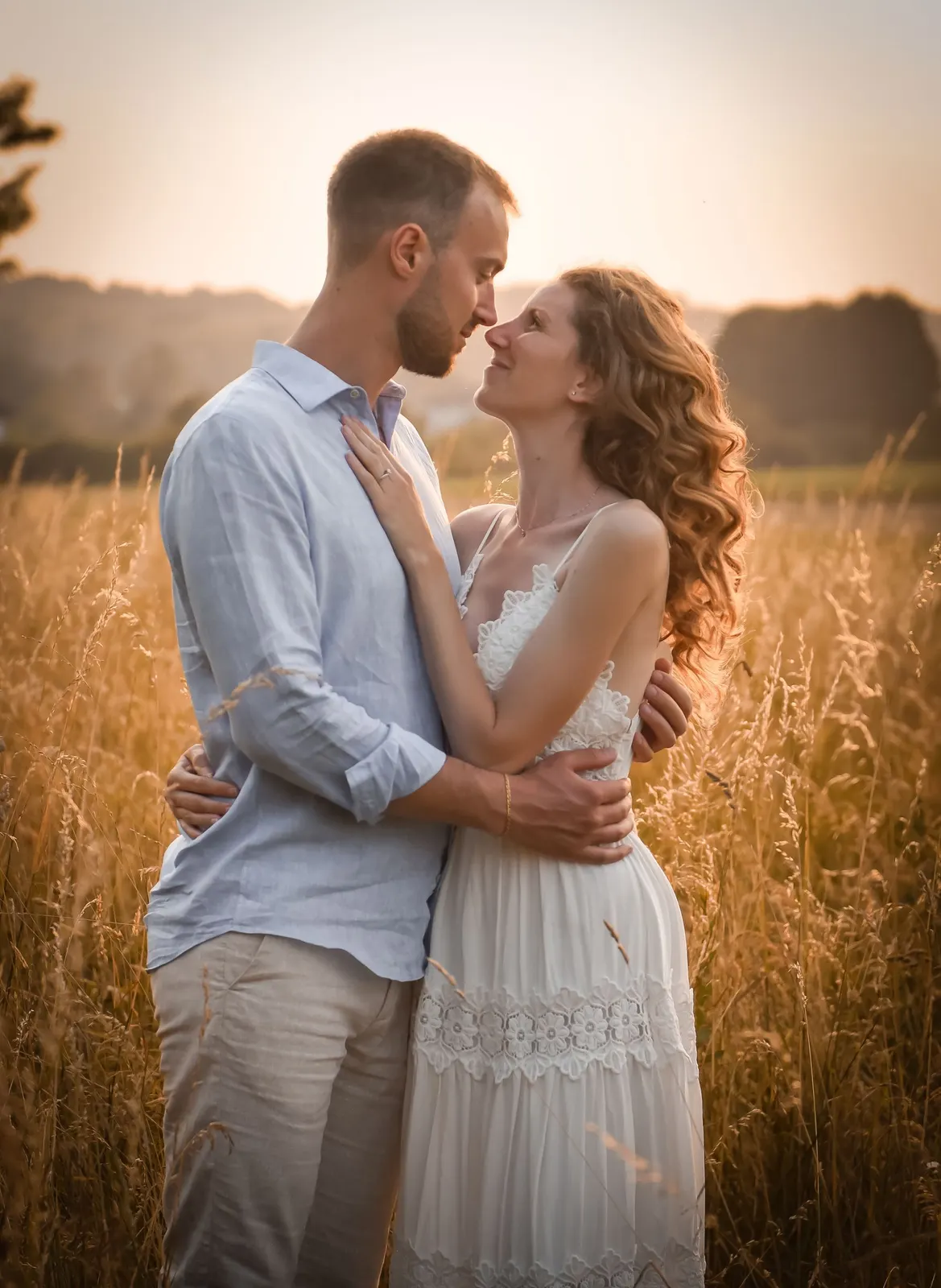 An engaged couple embracing in a golden field (sample image)